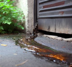 Fuite accidentelle d'huile s'écoulant vers un jardin, illustrant une pollution de terrain